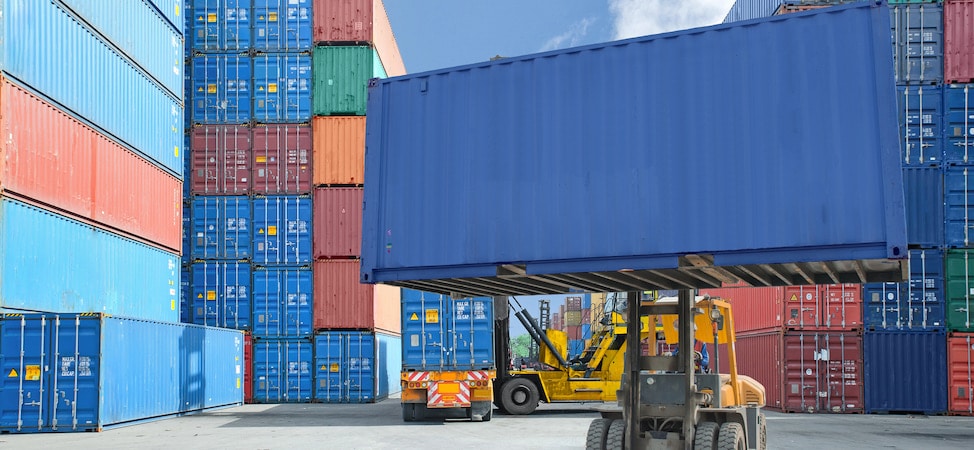 Forklift lifting shipping container in cargo yard