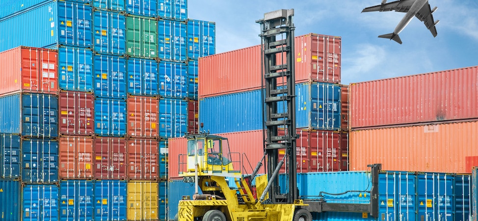 Forklift moving shipping containers at busy cargo port
