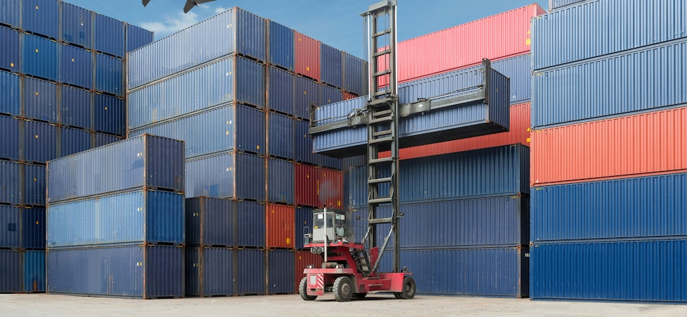 Stacked shipping containers with forklift lifting container