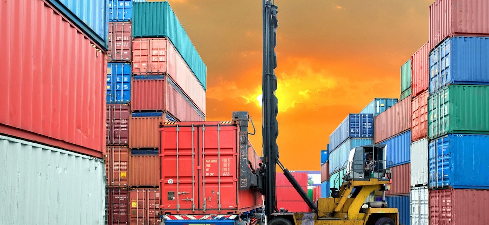 Stacked shipping containers at port during sunset